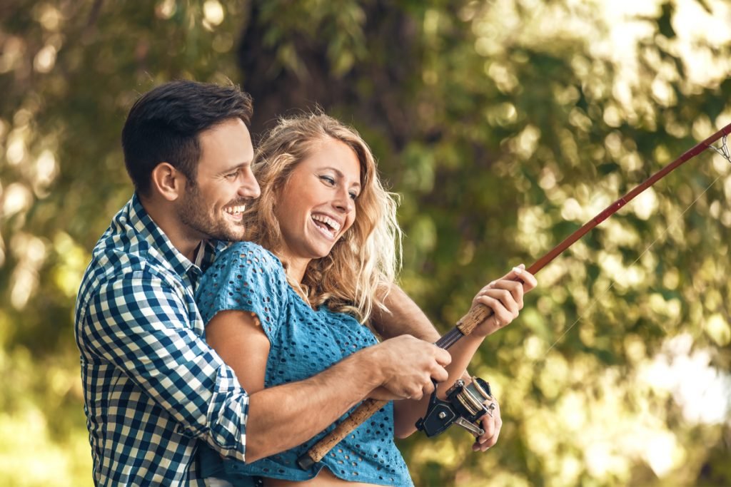 2 young adults laughing while fishing