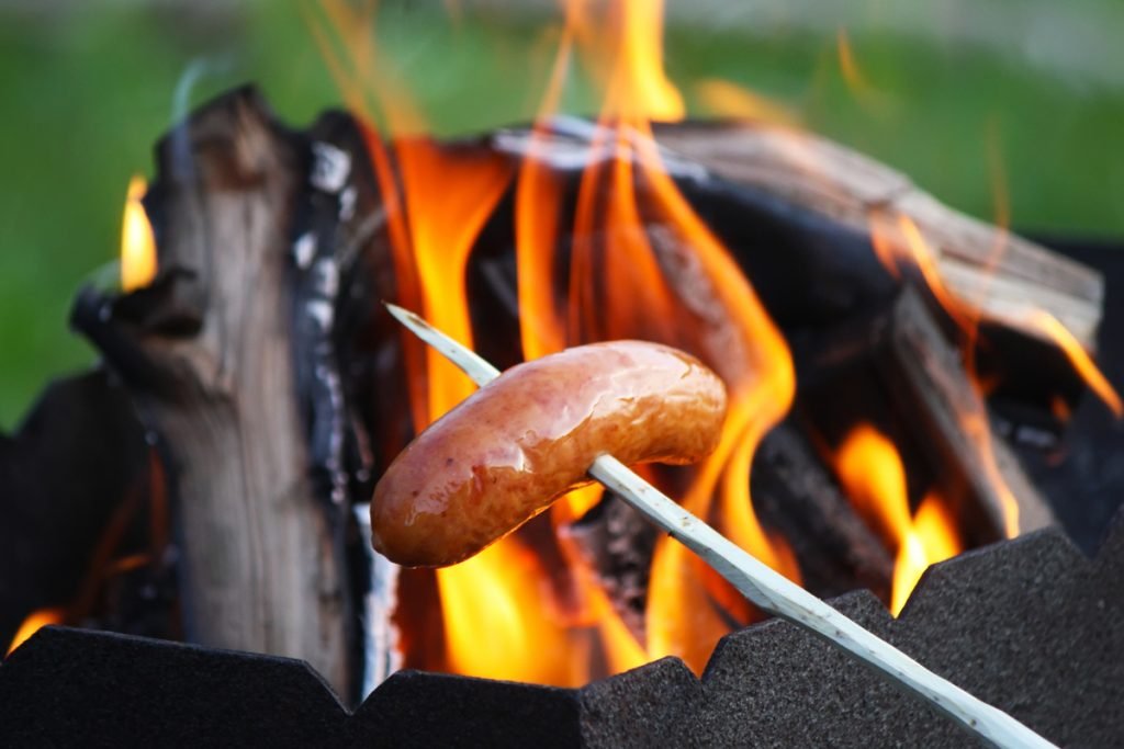 Cooking Sausage on a stick over the flames of a small campfire