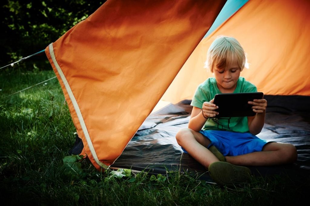 boy in lit tent avidly looking at a tablet computer