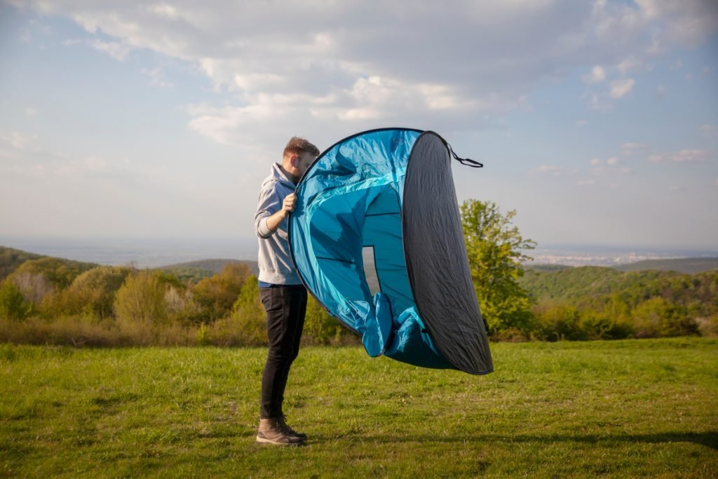 Man opening pop up tent. Do pop up tents come with pegs