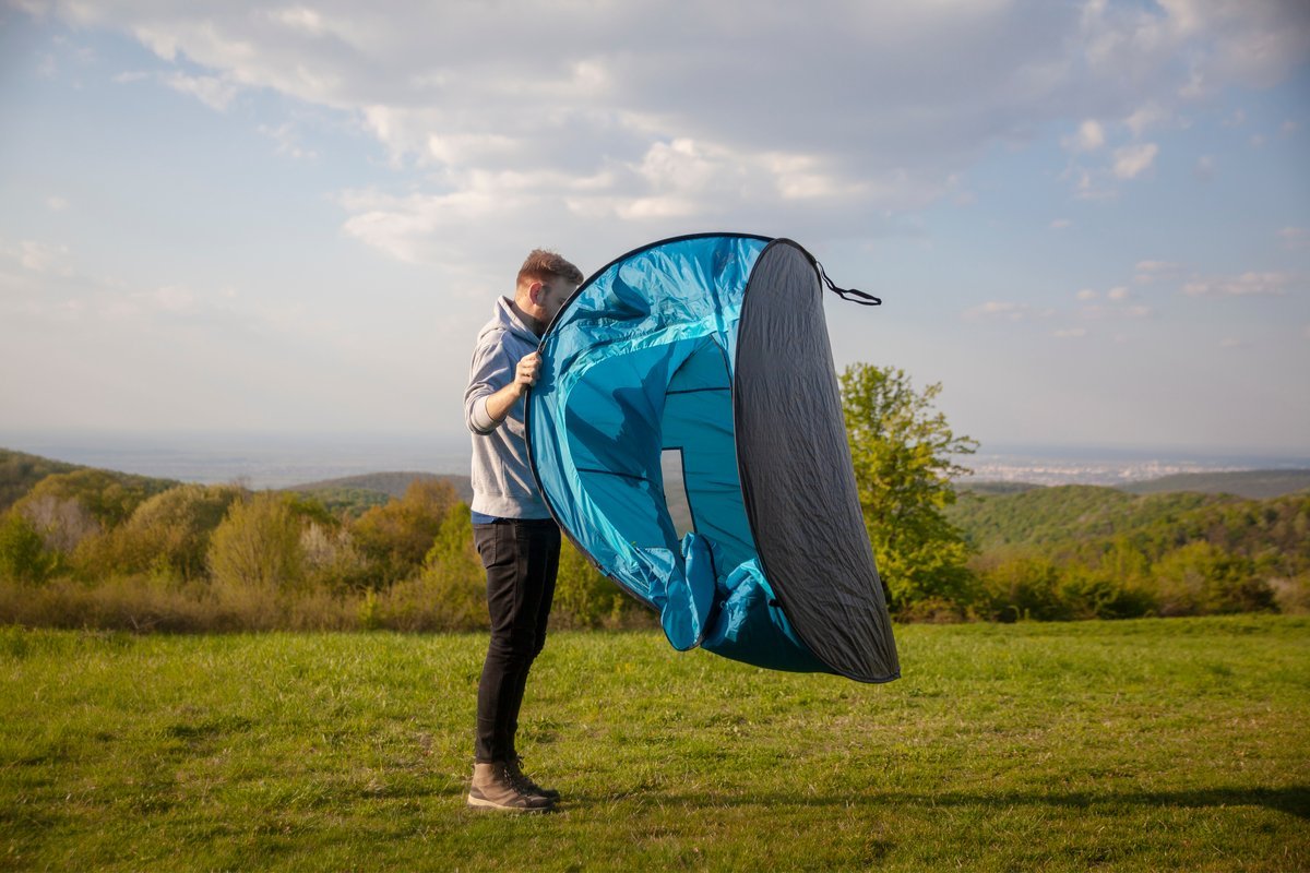 Man opening pop up tent. Do pop up tents come with pegs